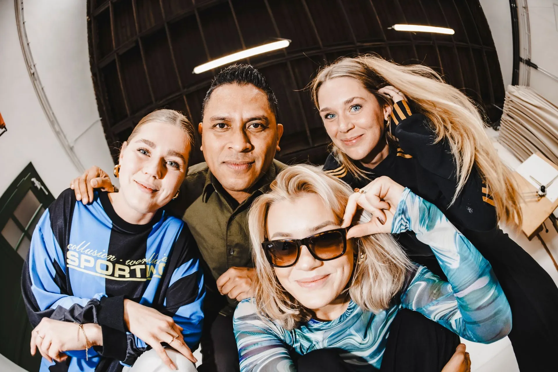 Vier teamleden van Sjraar poseren dicht bij elkaar voor een fisheye-foto in de studio