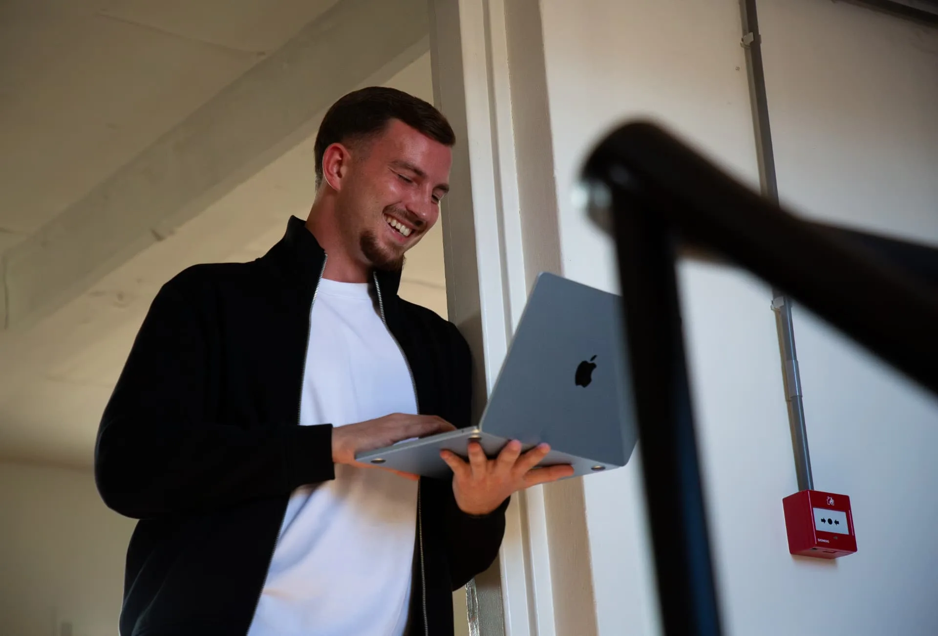 Gielke Huijs lacht terwijl hij op zijn laptop aan een website werkt